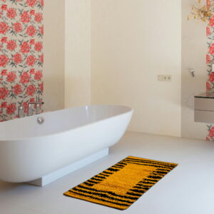 "Modern bathroom with a freestanding white bathtub and a bold yellow and black striped bath mat on a white tiled floor, complemented by floral wallpaper and elegant decor."